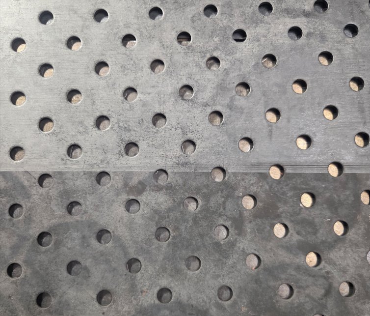 Détail d’un plateau perforé : surface nettoyée au laser au-dessus, surface calaminée en dessous